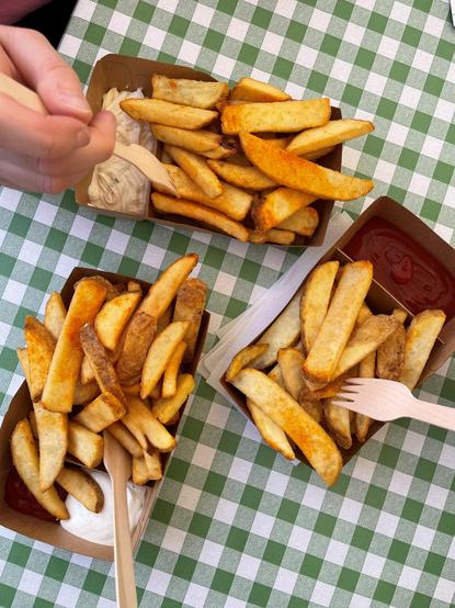 drei Portionen Pommes auf grün karierter Tischdecke