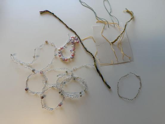 Gebastelte Armbänder aus Draht und Perlen liegen auf einem Tisch.
